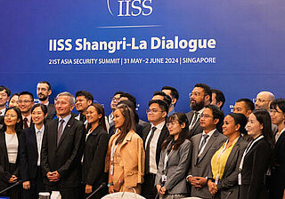 IISS Conference – Group on Stage A group of people standing together on stage at the IISS conference.
