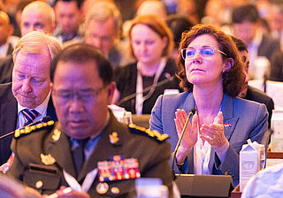 IISS Conference – Audience Perspective Audience at the IISS conference, with microphones placed on the tables in the front rows.