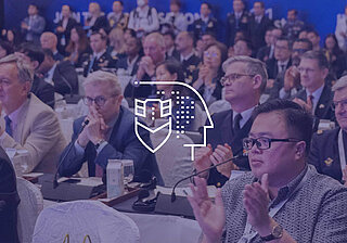 GSIS 2025 Conference – Visual Spotlight People in the background with a central white graphic symbolizing a theme, used as part of the GSIS 2025 conference visuals.